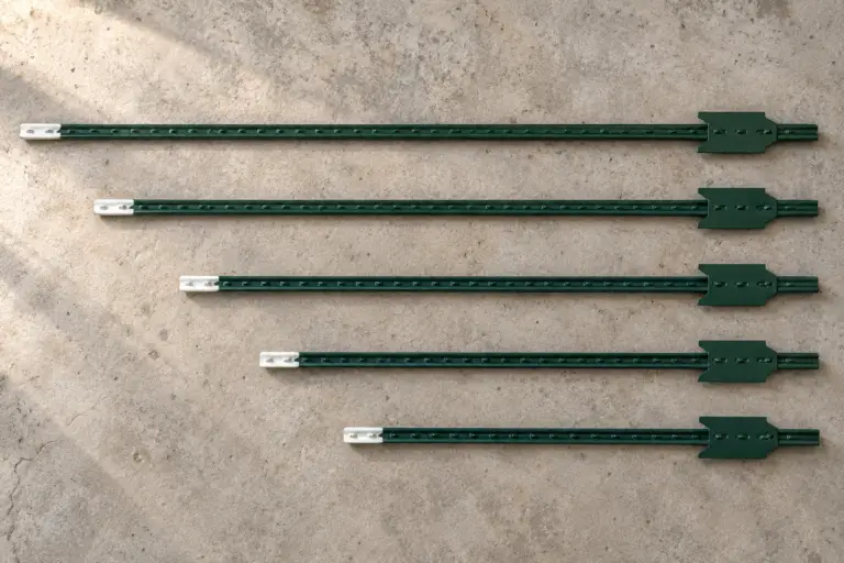 Five green steel T-posts in different lengths arranged from longest to shortest, with white tips and aligned anchor plates.